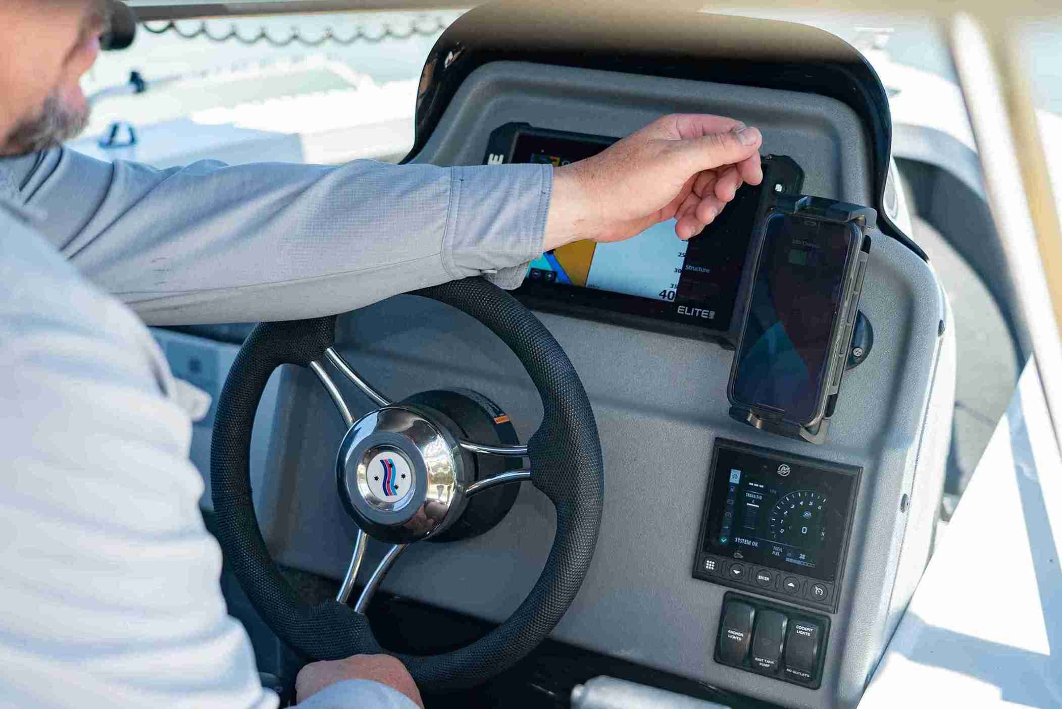 Boat helm station console with a steering wheel, marine navigation screen, and phone mount.